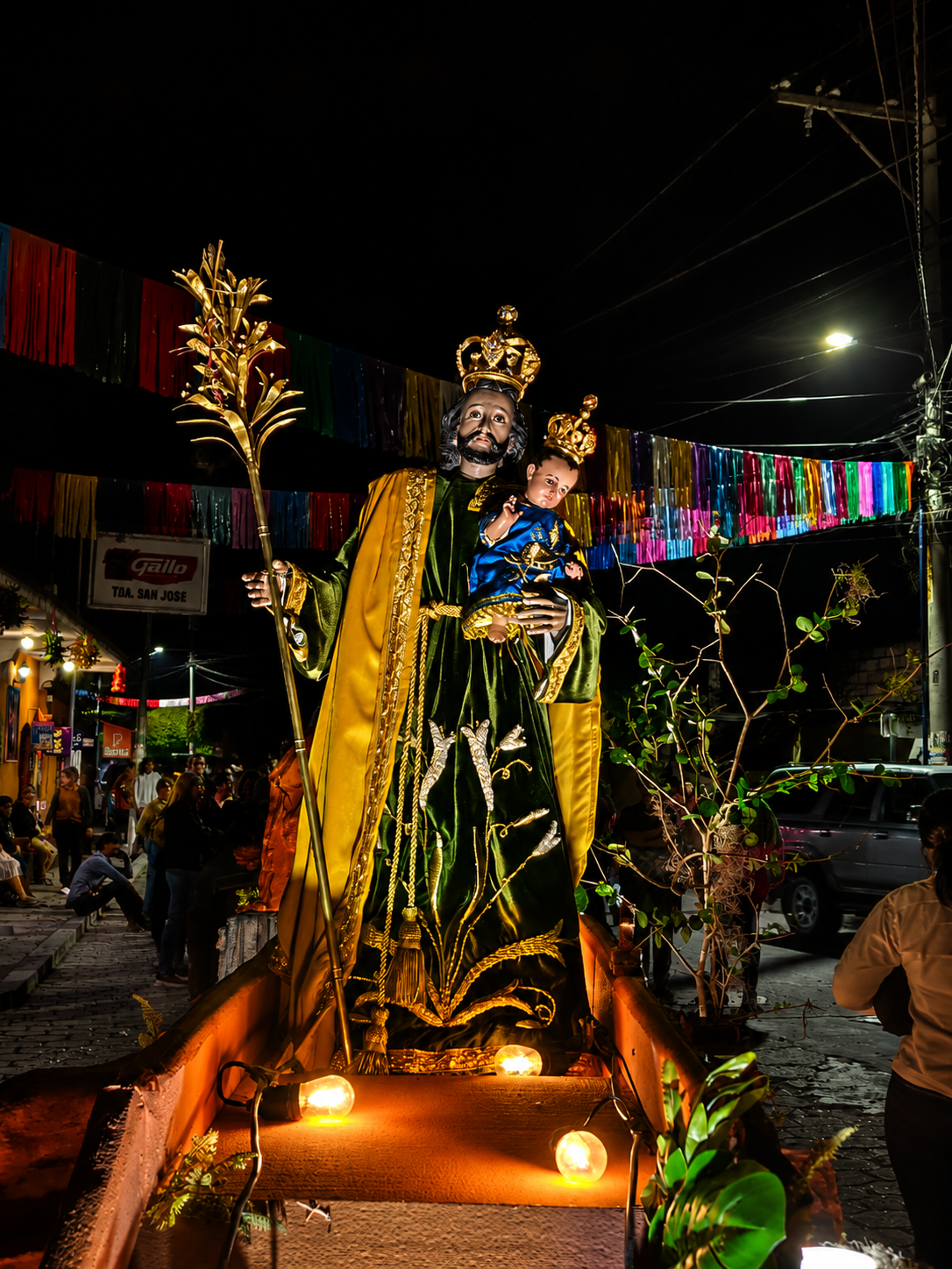 Procesión religiosa pasando frente a una iglesia con fieles acompañando